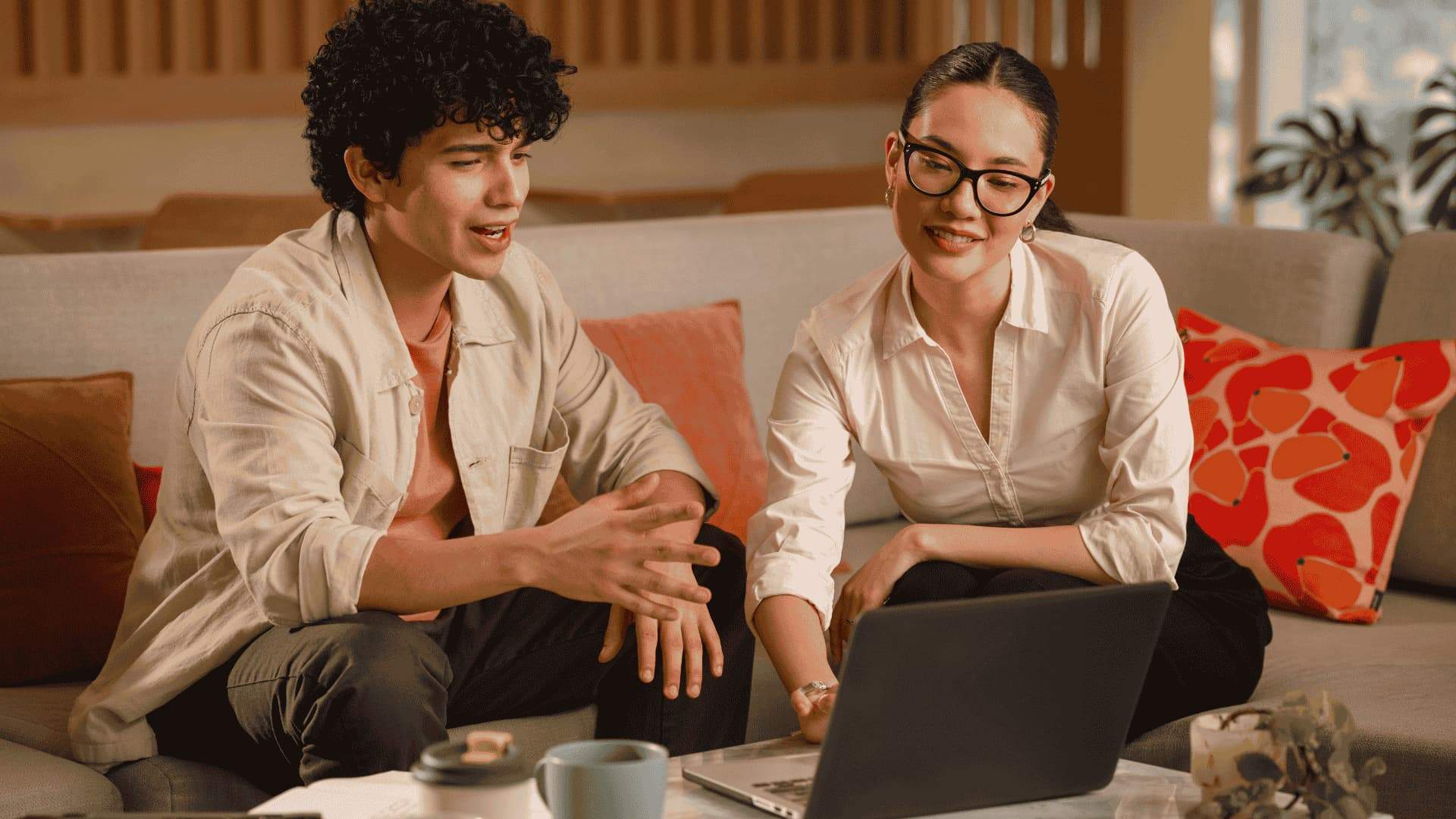 Engineers discussing a project in front of a laptop, sitting on a sofa in a relaxed environment.