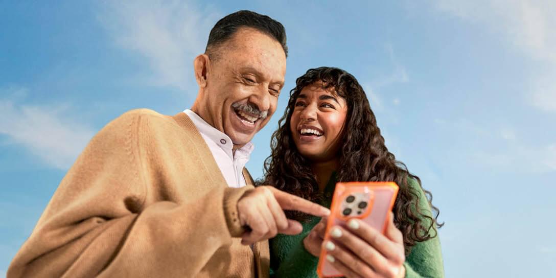 A man and woman laughing while looking at a phone