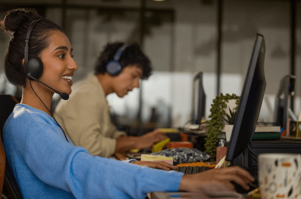 Smiling customer support agent using a digital dashboard to manage and analyze unified customer data.