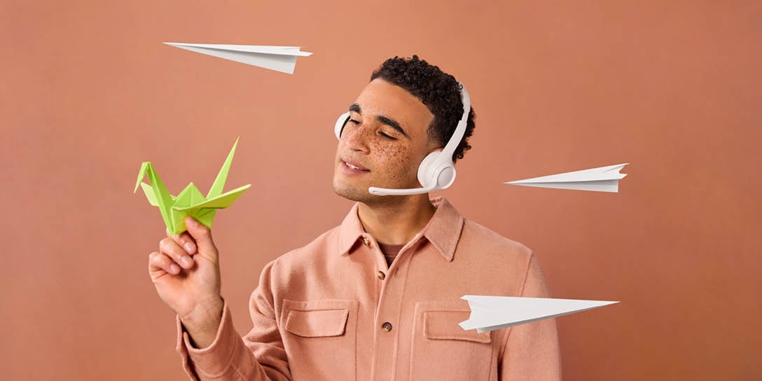 A customer service agent holds a paper crane while paper planes fly through the air.
