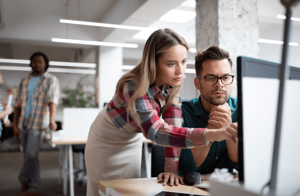 Team reviewing FAQ page examples on a desktop computer to improve customer self-service experience.