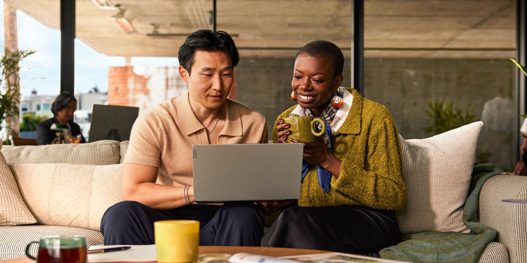 Two colleagues smiling while looking at a laptop, representing positive ITSM trends in a modern office setting.