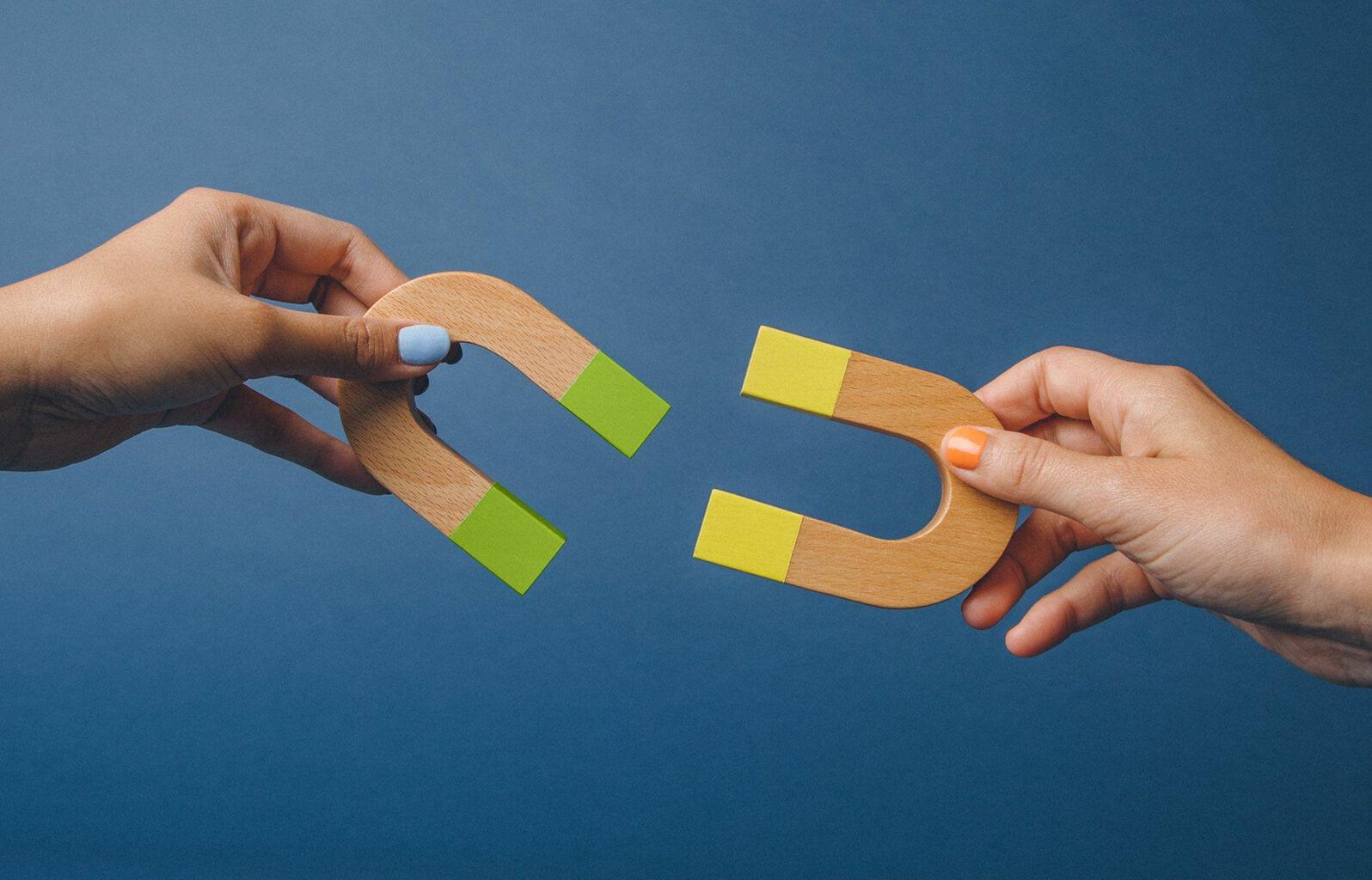Hände halten bunte Holzmagnete in U-Form