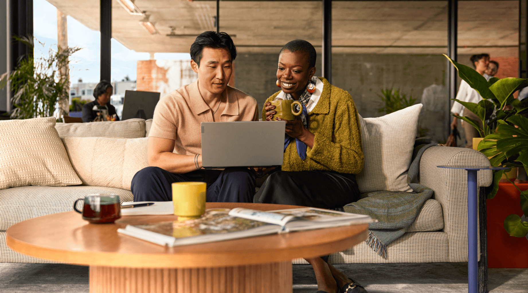 Two support professionals review customer service performance data on a laptop, representing AutoQA (automated quality assurance).