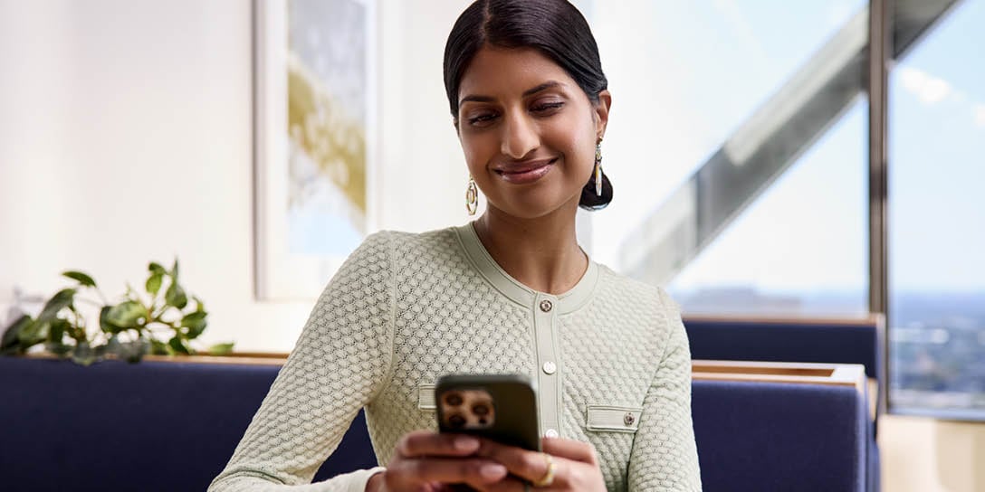 A smiling customer using a smartphone, representing efficient digital employee service interactions.