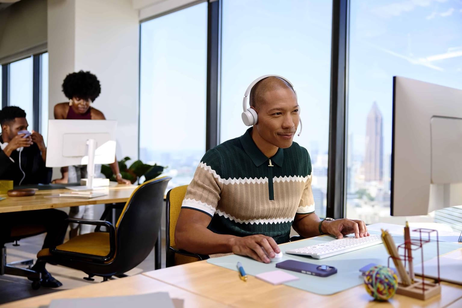 A person sitting at a computer with a giant hand throwing a paper airplane behind them.