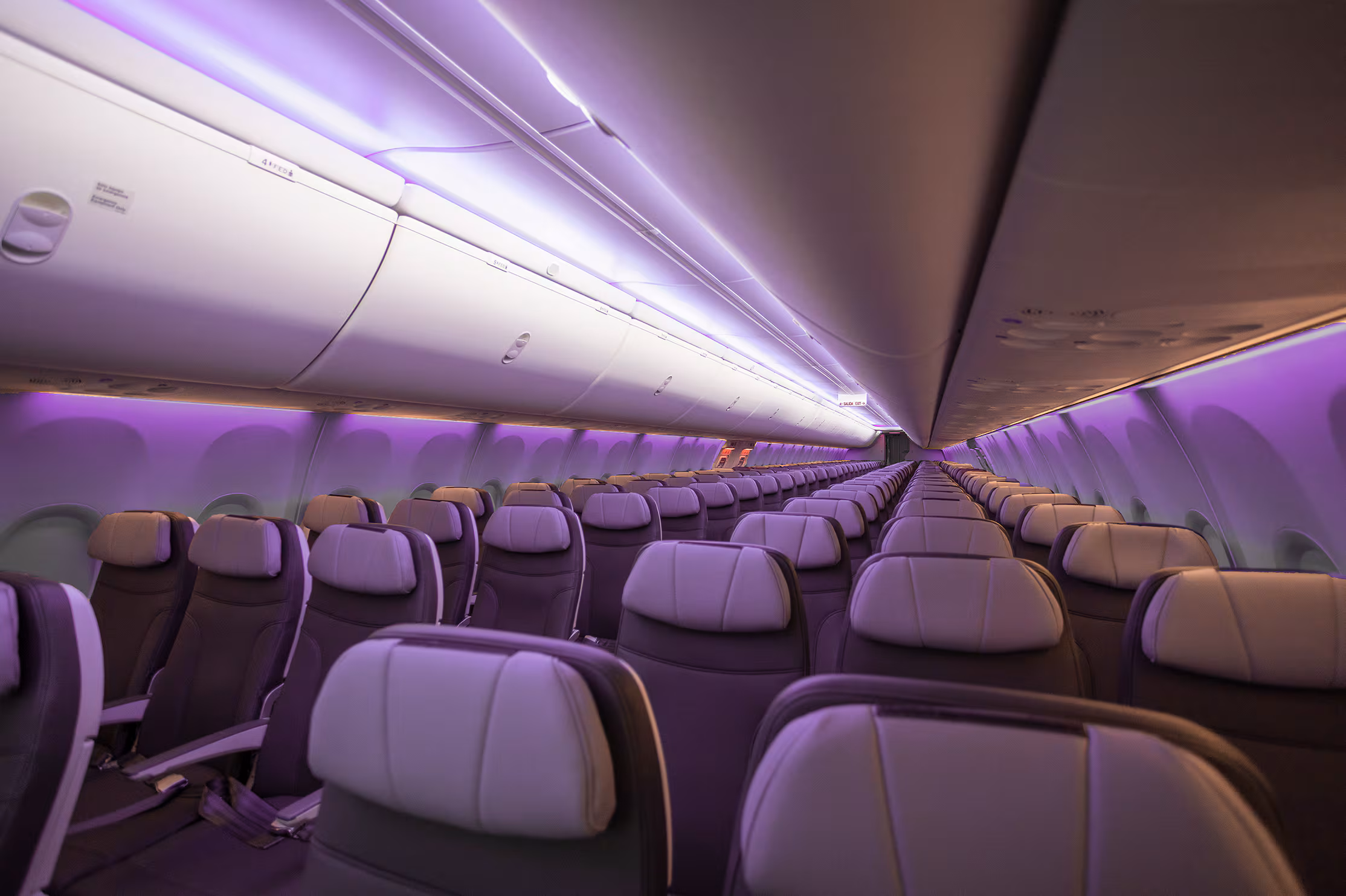 Interior of an Arajet airplane, cast with purple LED lights