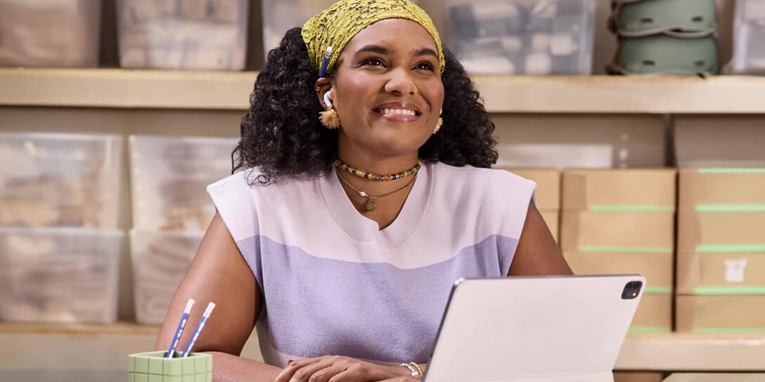 A person uses wireless headphones and a tablet to interact with human-centered AI for HR teams.