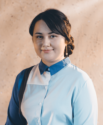 Photo: Portrait shot of a young woman, wearing a blue button up shirt.