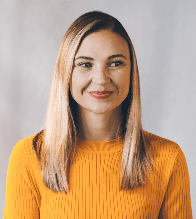 Photo: Portrait of a young woman smiling, wearing a yellow sweater.
