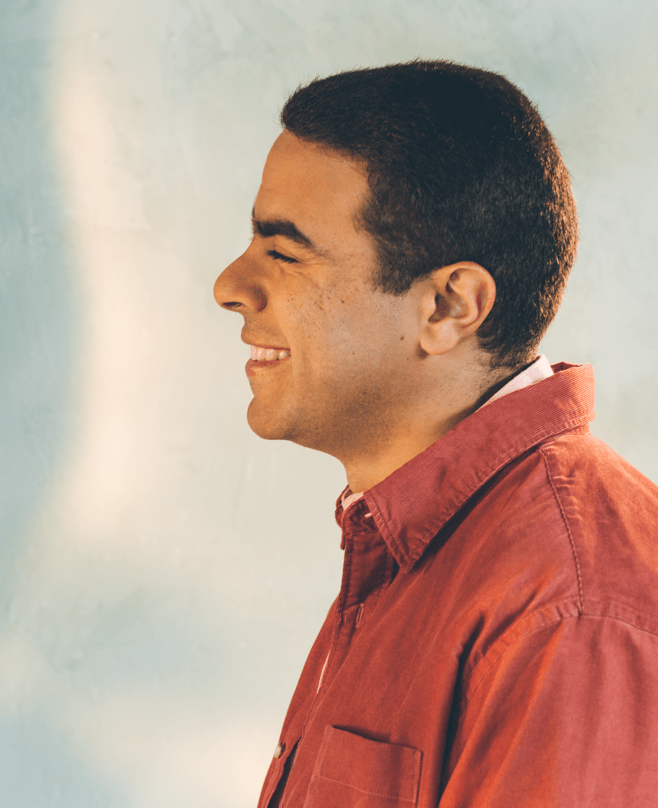 Photo: Portrait of young man smiling, wearing a red button up.