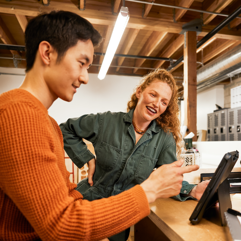 Two people looking at a tablet smiling and talking